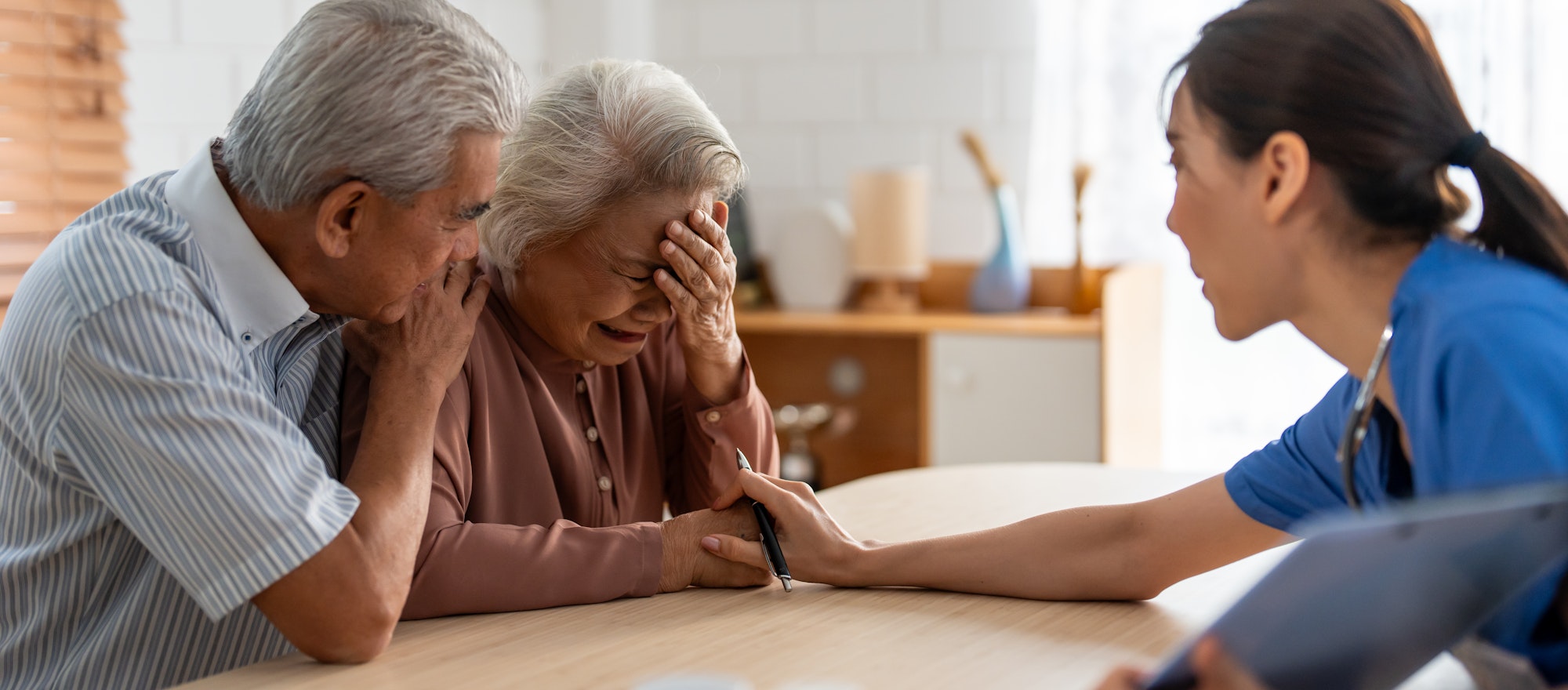Asian caregiver examine depress senior crying woman patient and husband.